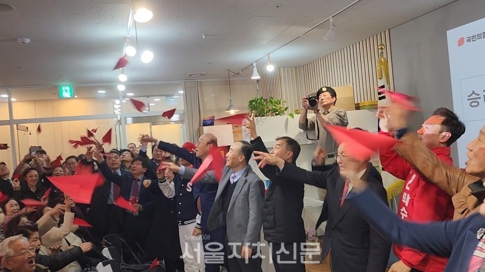 국민의힘 당선을 위해 개소식에서 한마음으로 붉은 색 종이비행기를 날리고 있다.
