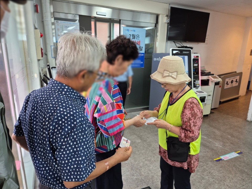 구로4동 주민센터 민생회복 소비쿠폰 전담창구에서 자원봉사자가 방문 주민에게 신청 방법을 안내하고 있다.